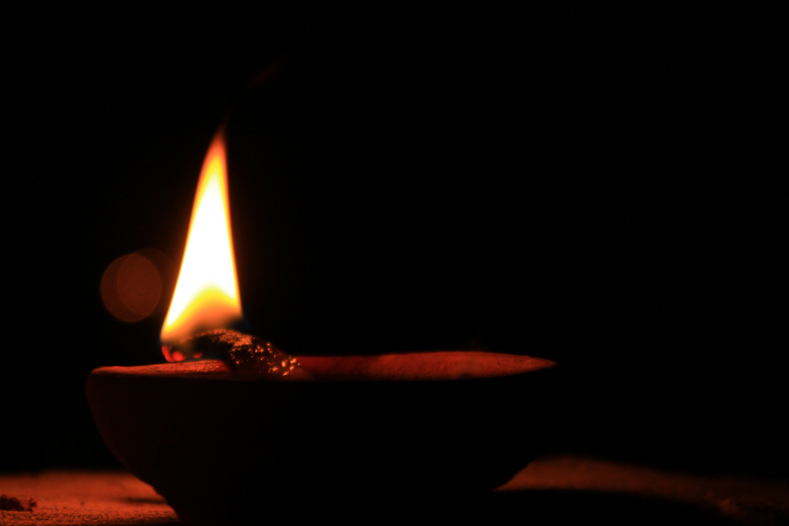 Bright burning wooden stick on stone bowl in darkness